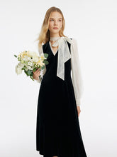 A blonde lady wears a black dress to a masquerade party.